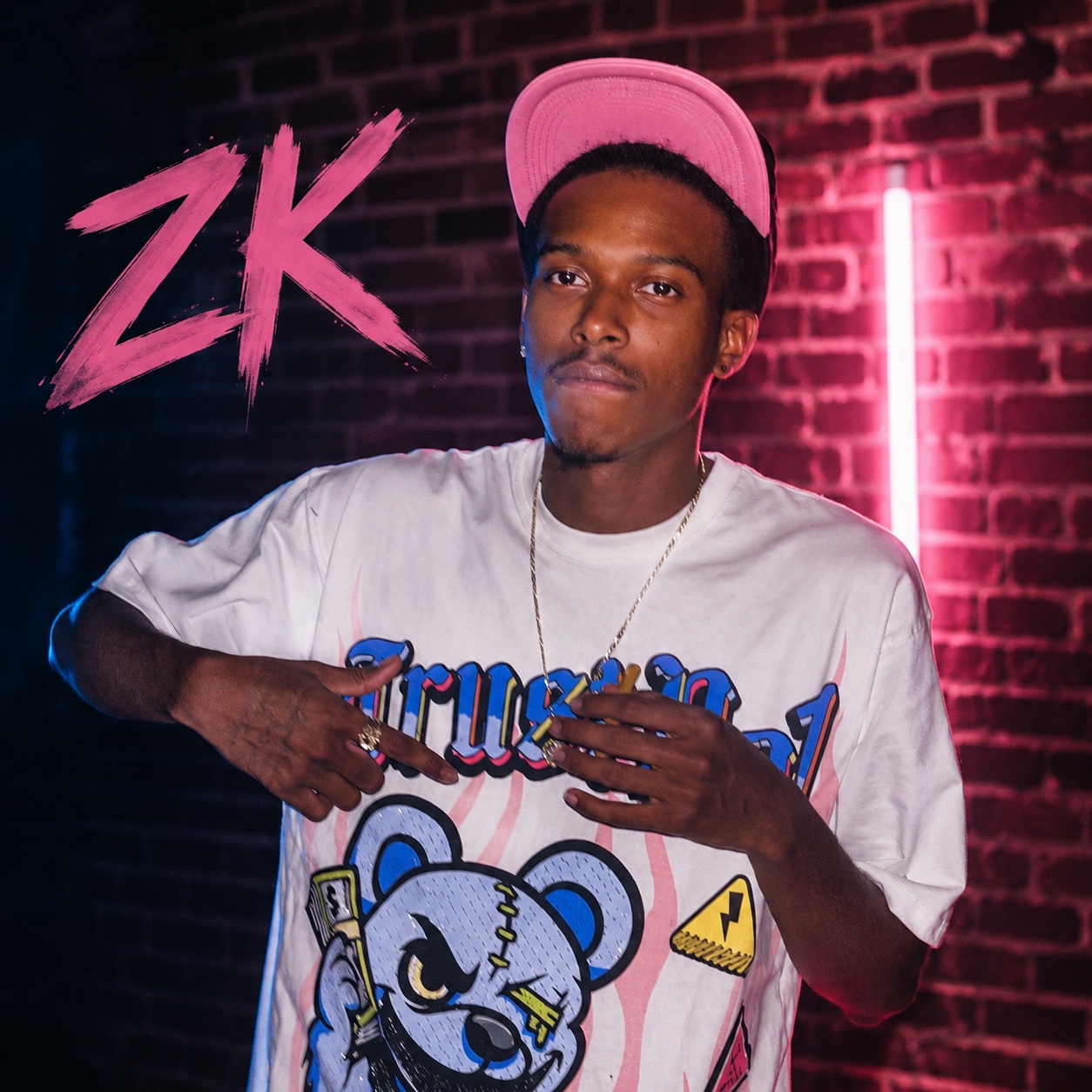 ThatBoyZK posed against a brick wall under hot-pink and electric-blue lighting
